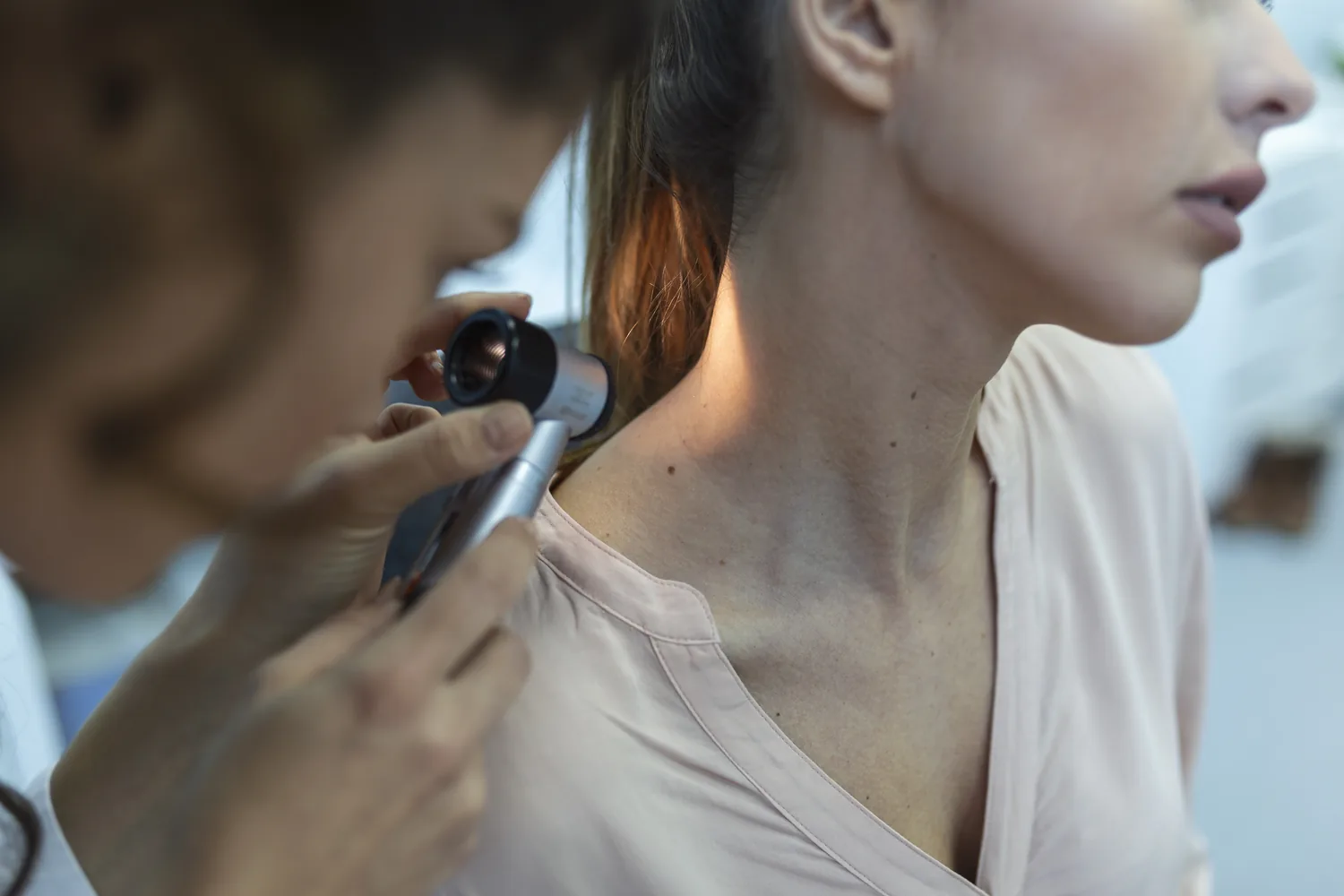 Naturopathic physician examining a patient’s skin with a dermatoscope during a functional dermatology evaluation in Kirkland, WA.
