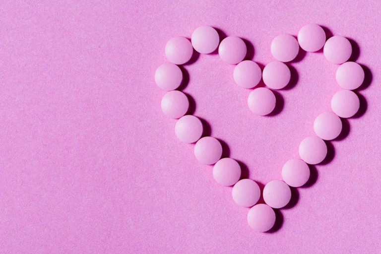 Pink round tablets arranged in a heart shape on a pink background, representing bioidentical hormone therapy options.